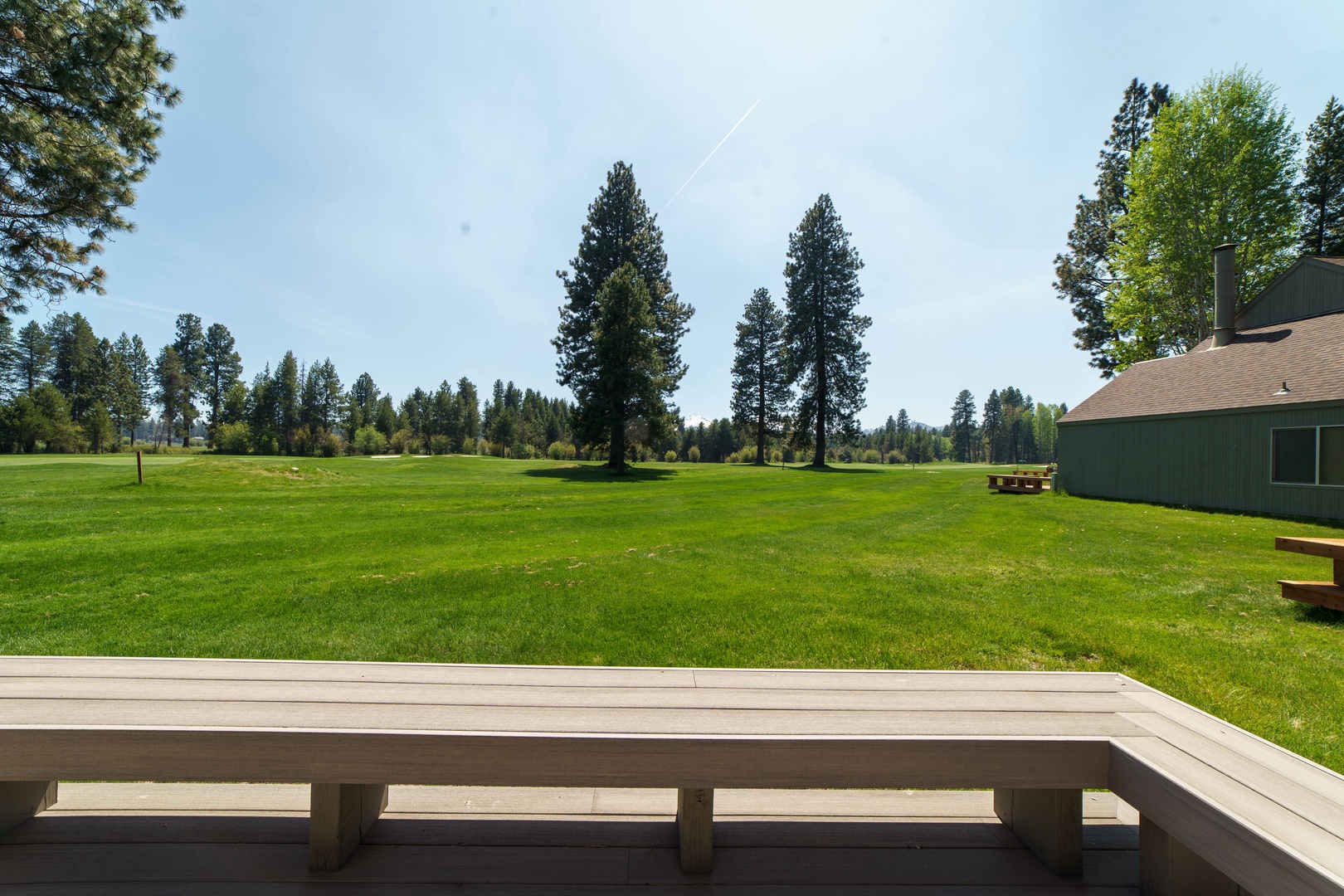 Expansive golf course views stretch across rolling greens, framed by towering pines under clear mountain skies.