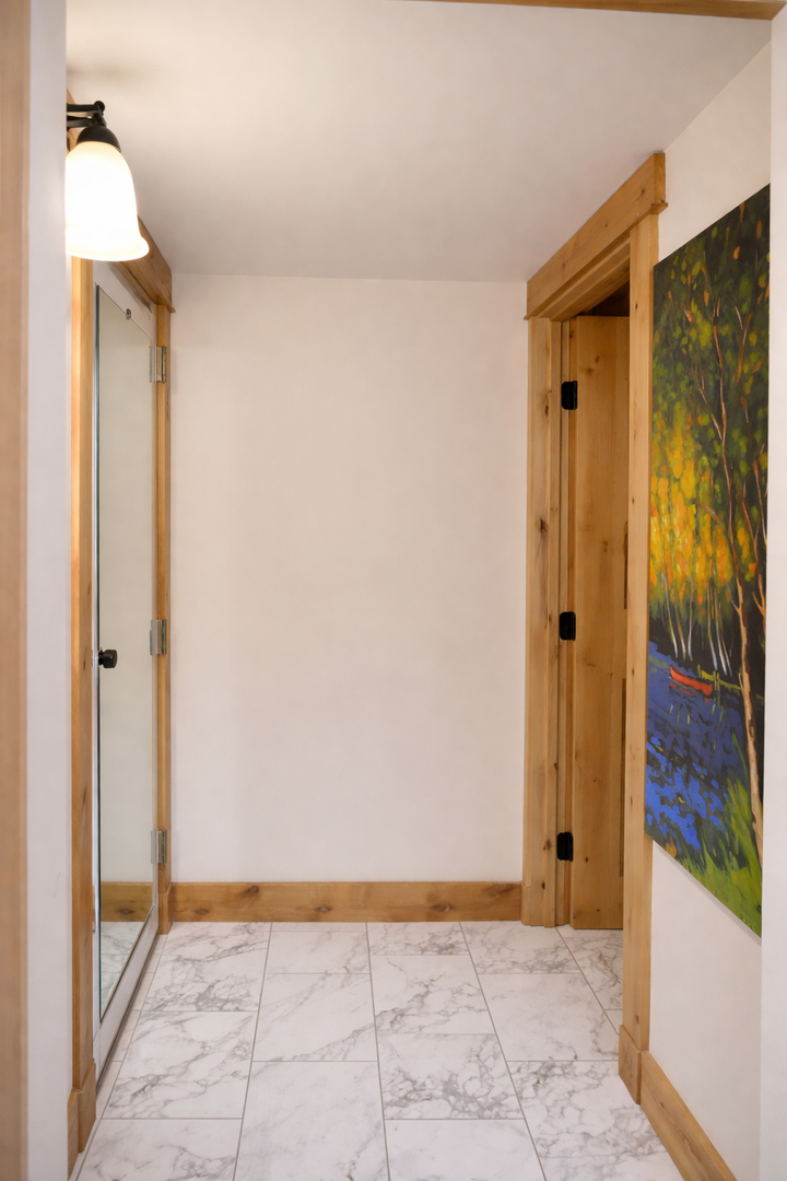 Step into your stylish entryway featuring warm wood accents, marble-effect flooring, and a full-length mirror that perfectly frames your arrival.