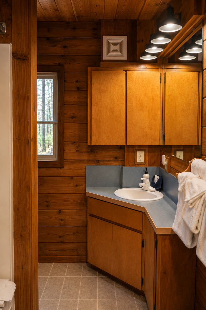 Step into your cabin-style bathroom with warm wood walls, modern lighting, and a sleek vanity—thoughtfully designed to make you feel at home in the woods.