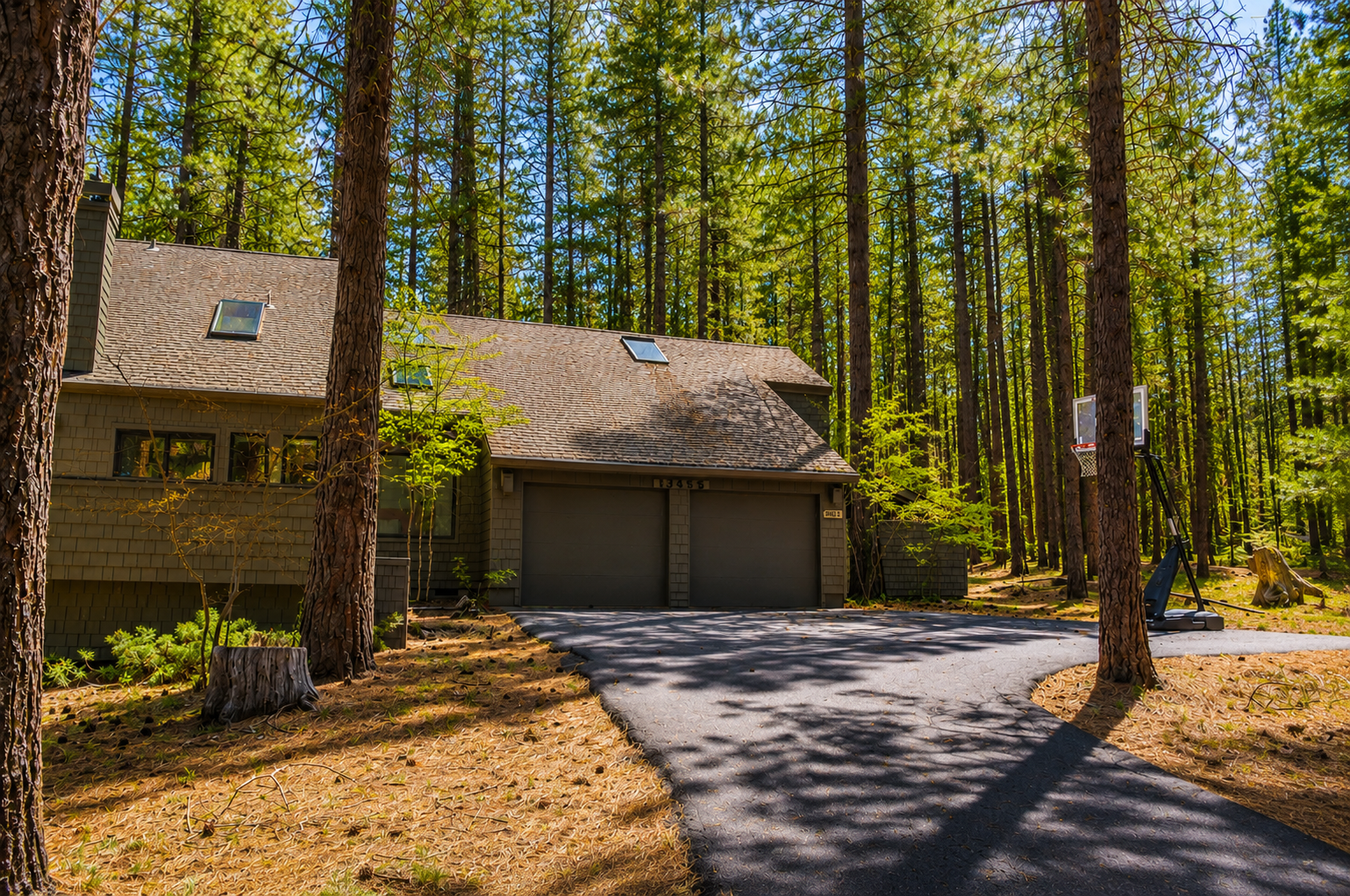 Private forest retreat with two-car garage nestled among towering pines, offering serene natural surroundings and easy arrival via paved driveway.