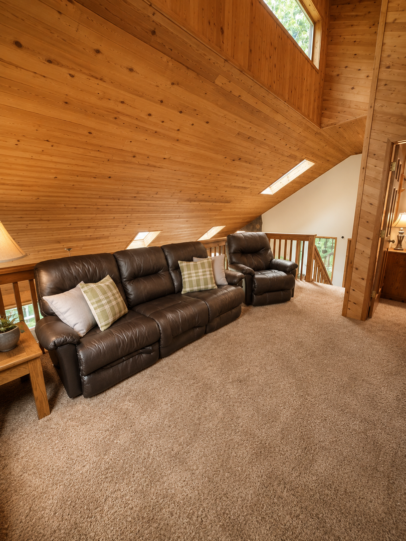 Sink into soft leather seating in your cozy loft lounge, where warm pine walls and vaulted ceilings create a peaceful retreat. Natural light pours through skylights above.