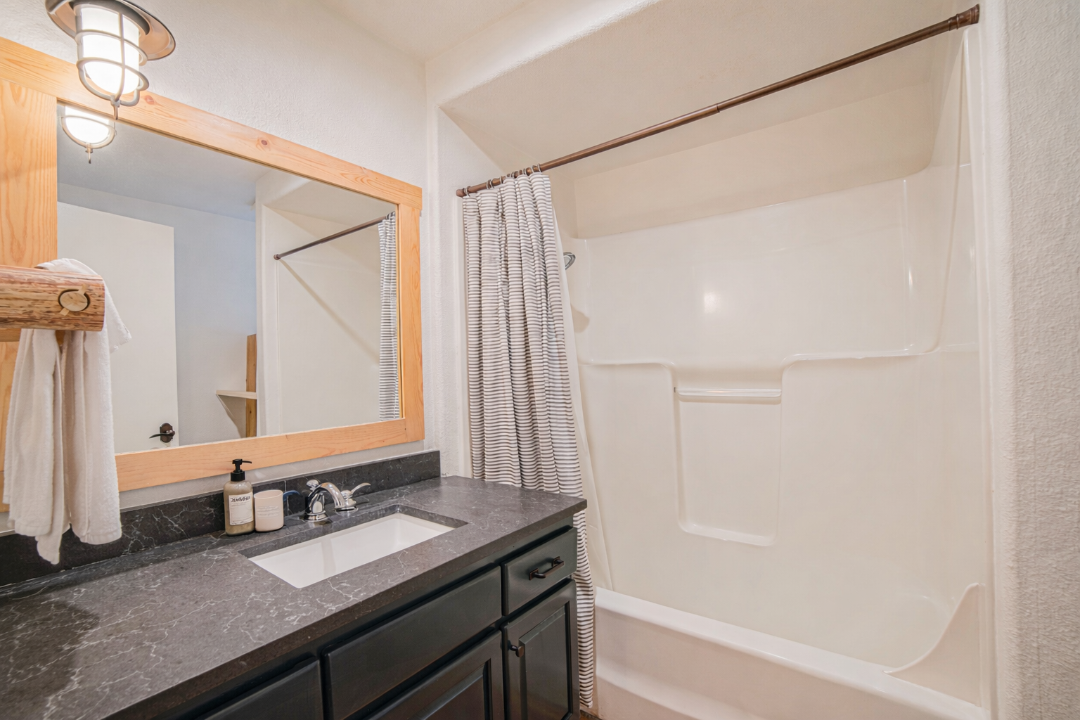 Unwind in your spotless bathroom featuring a spacious tub-shower combo, granite vanity, and cozy nautical touches for ultimate relaxation.