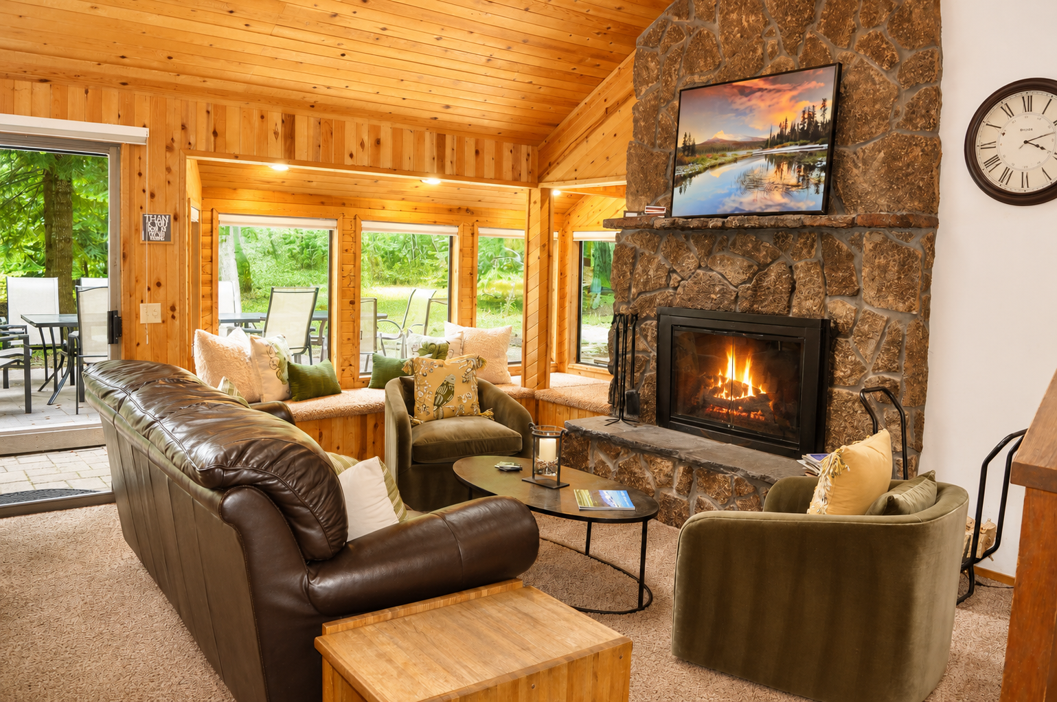 Sink into plush seating by your crackling stone fireplace as natural light pours through expansive windows overlooking lush greenery. Your cozy retreat with warm wood tones awaits.