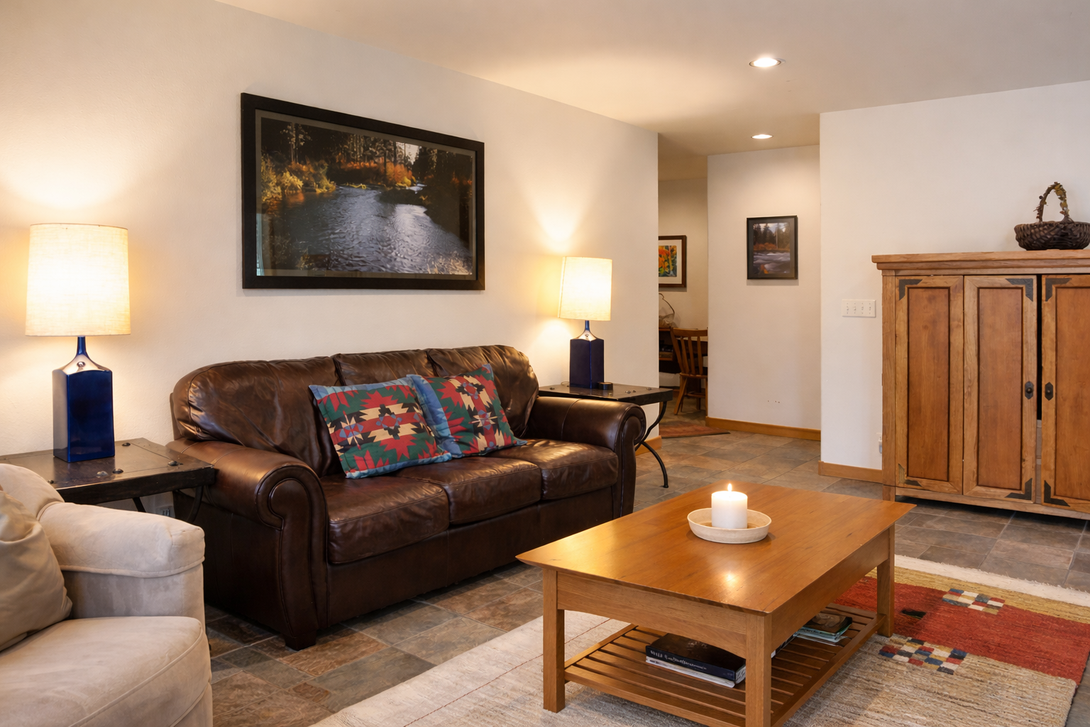 Sink into plush leather seating by warm lamplight, where thoughtful decor and a flickering candle create your perfect evening retreat.