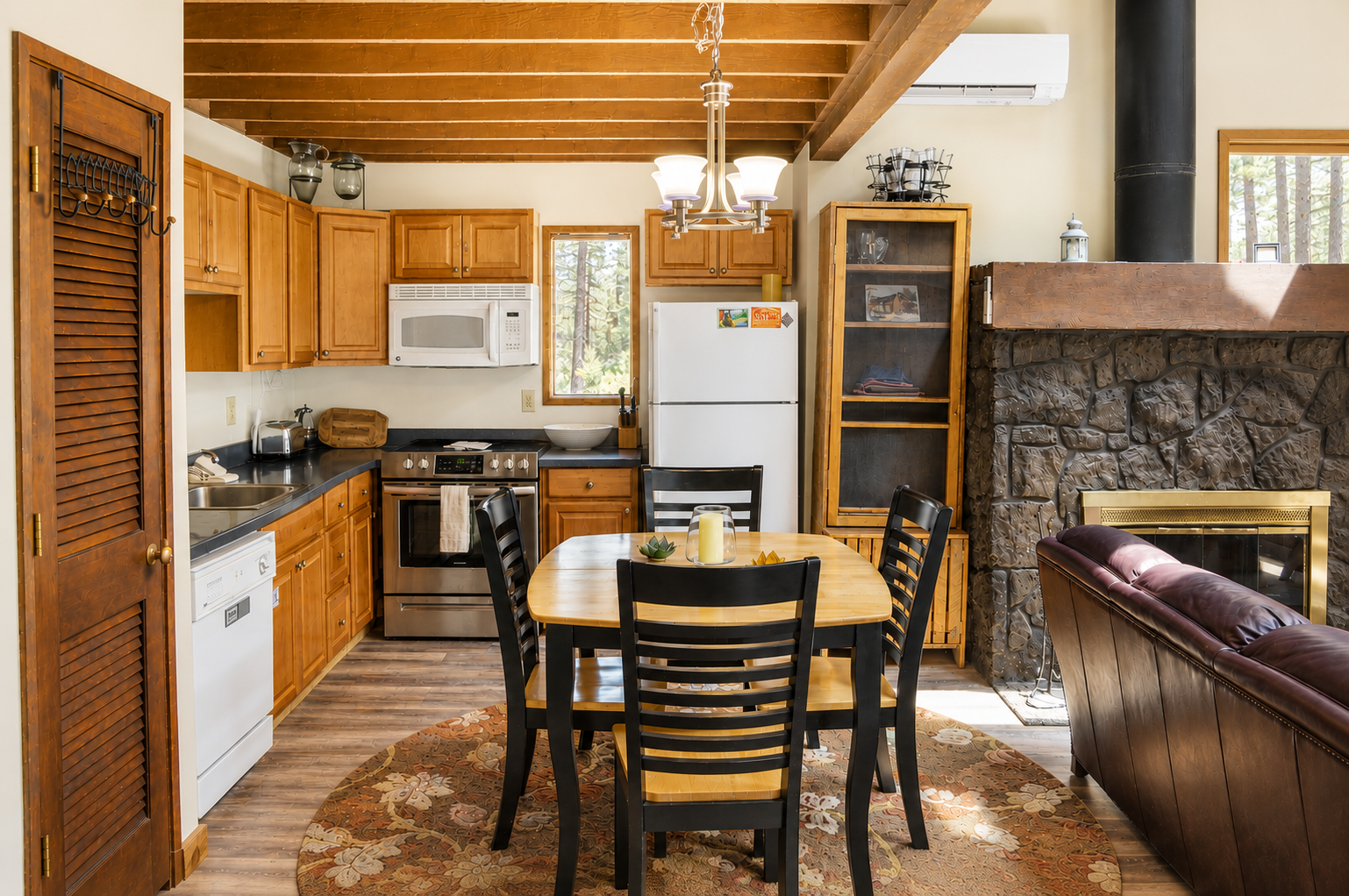 Gather around the dining table in this warm, open-concept space where exposed beams meet modern convenience. Your fully equipped kitchen invites meal prep, while the stone fireplace creates cozy ambiance for memorable evenings together.