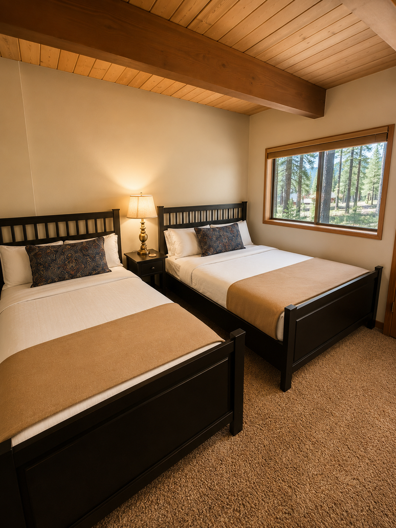 Unwind in your cozy bedroom with two plush beds dressed in crisp white linens. Natural light streams through windows framing forest views, while warm wood ceilings and soft carpeting create your perfect mountain retreat.