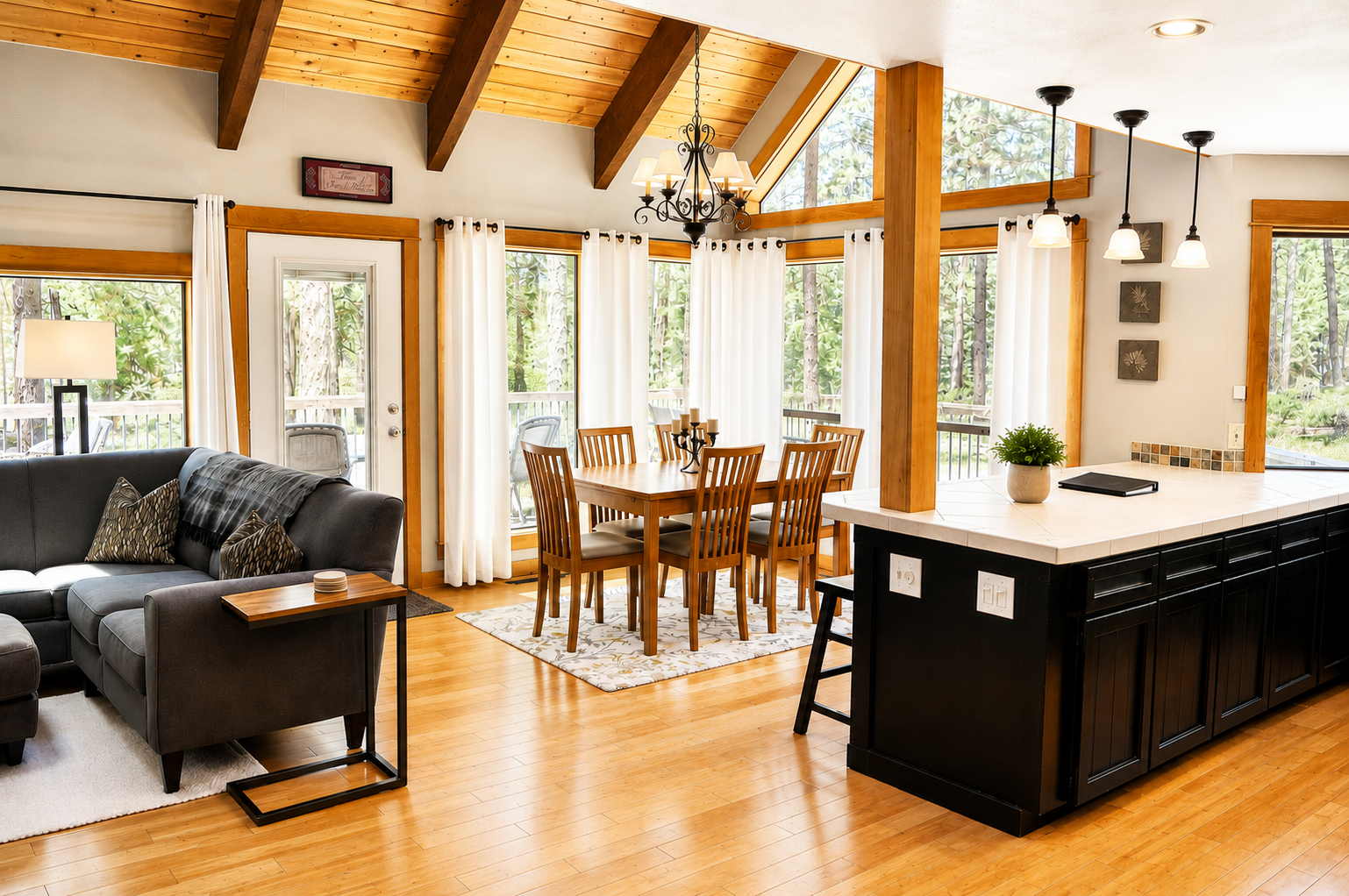 You'll love unwinding in this bright open-plan living space with vaulted wood ceilings, where sunlight pours through floor-to-ceiling windows and invites you to gather around the dining table or relax on the sofa.
