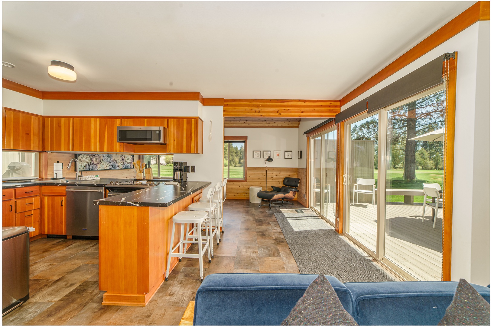 Gather in this open-plan space where warm wood tones meet modern comfort, featuring a full kitchen and sliding doors to your private deck.