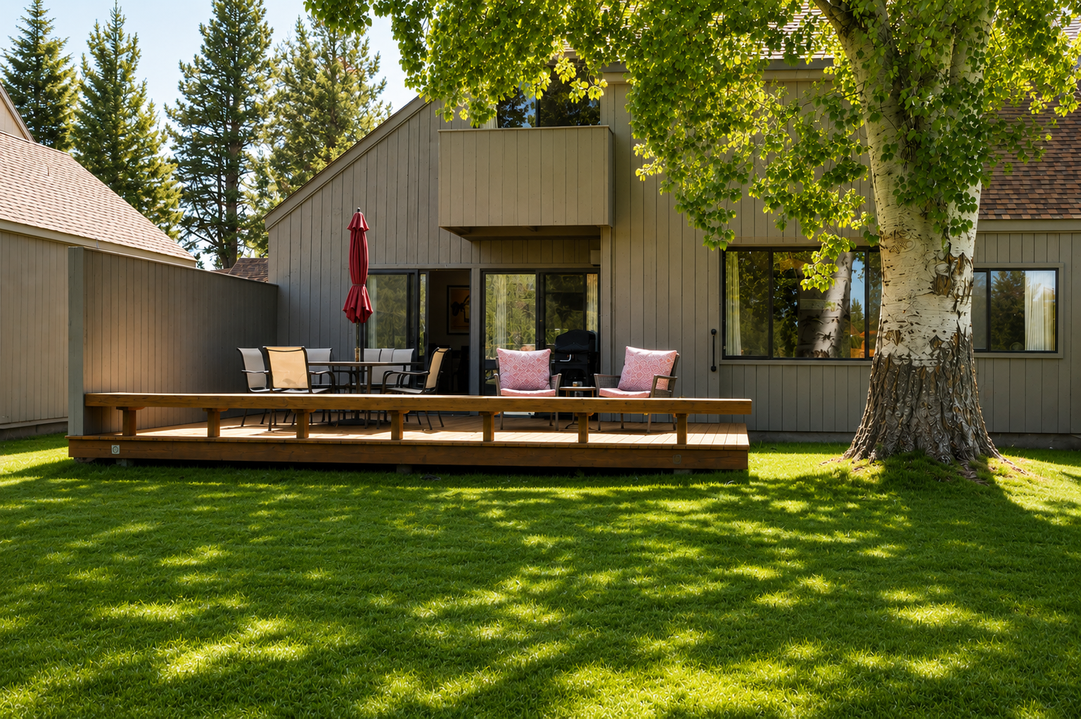 A modern retreat surrounded by mature trees and lush lawn, featuring a spacious deck for outdoor relaxation and dining in a serene natural setting.