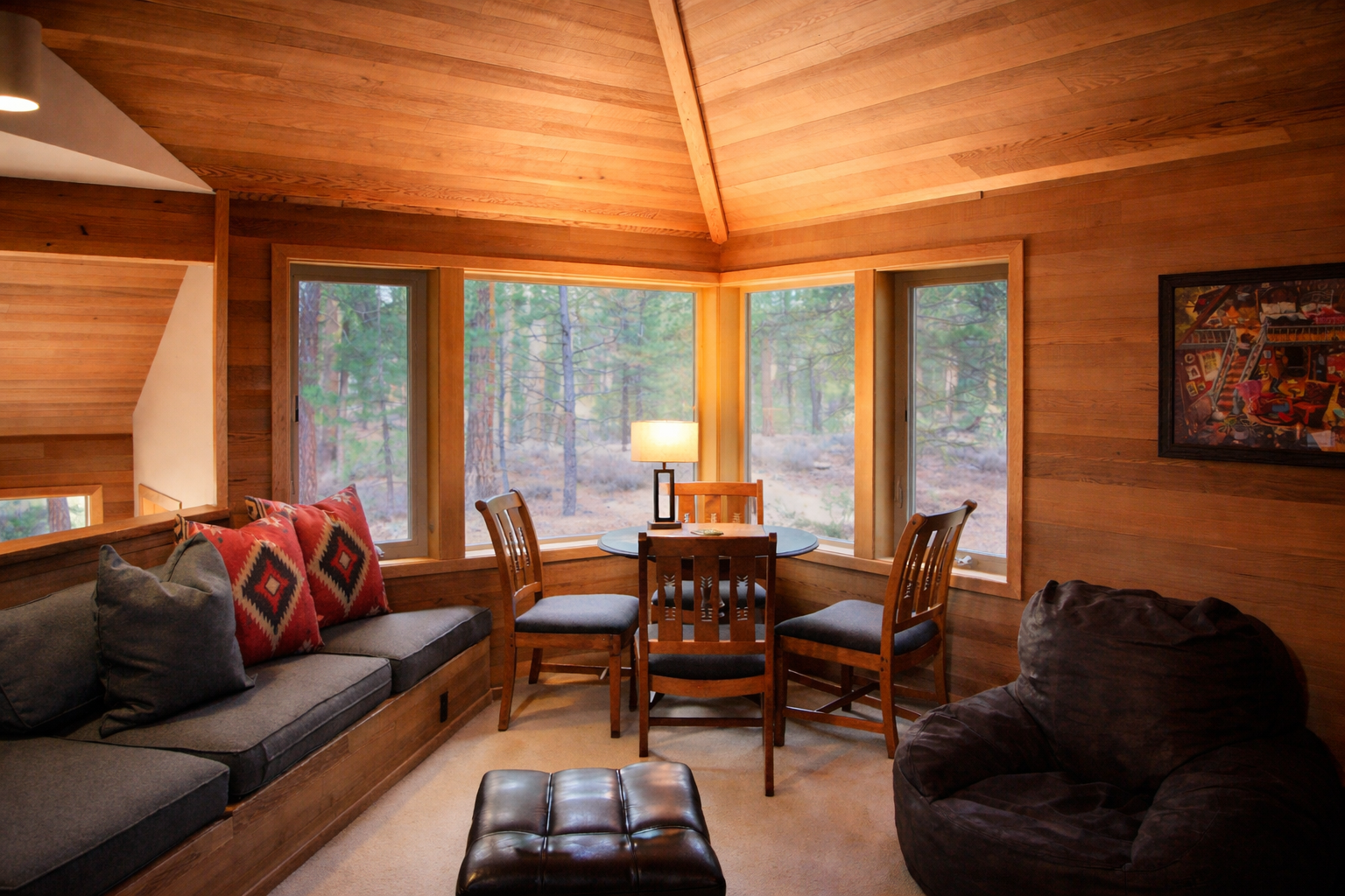 Curl up in your cozy wood-paneled retreat, where panoramic forest views through wrap-around windows create the perfect backdrop for relaxing evenings.
