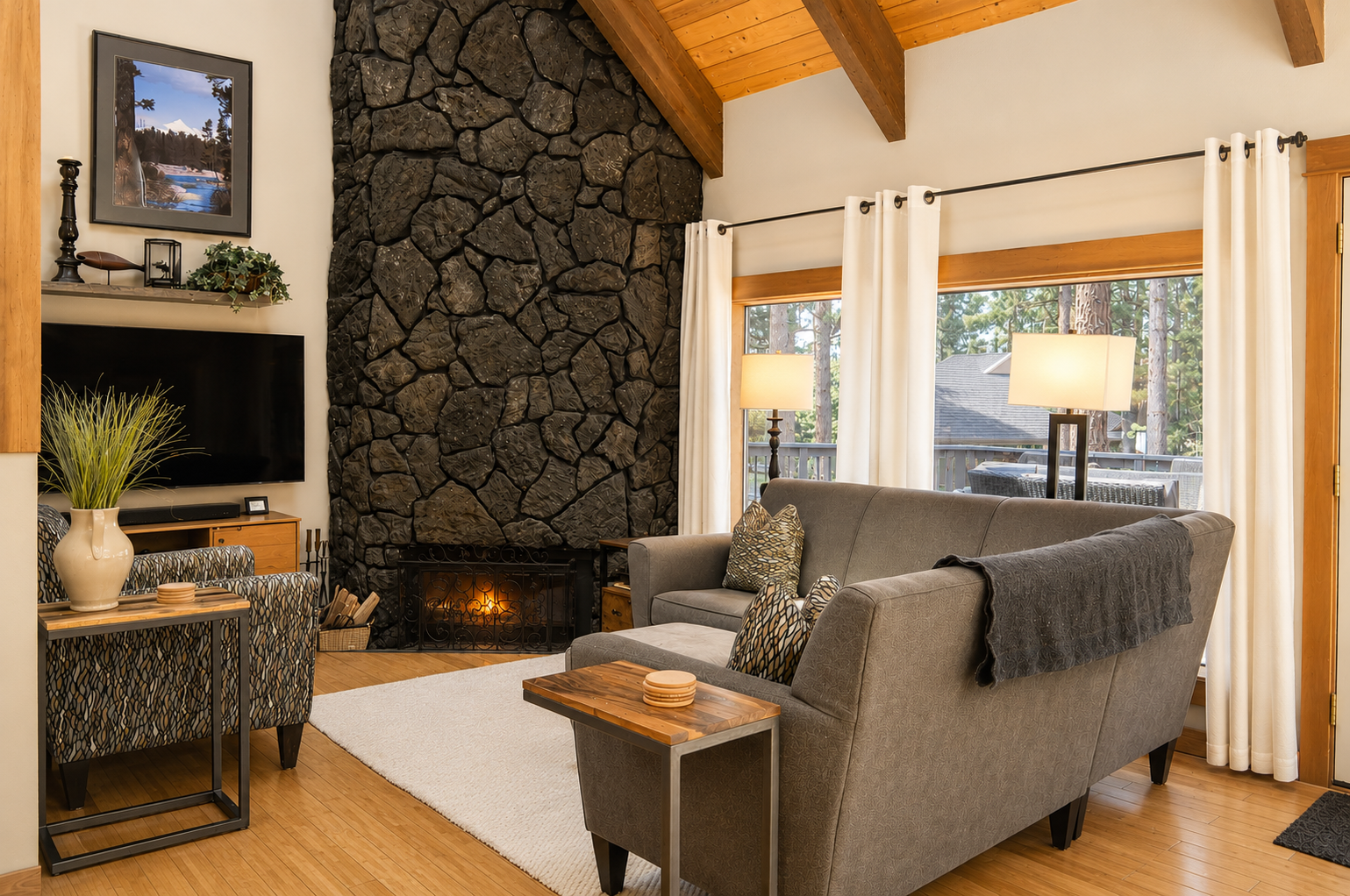 Unwind in this cozy living room where rustic stone meets modern comfort. You'll love the warmth of the fireplace, vaulted wood ceilings, and soft natural light pouring through the windows.