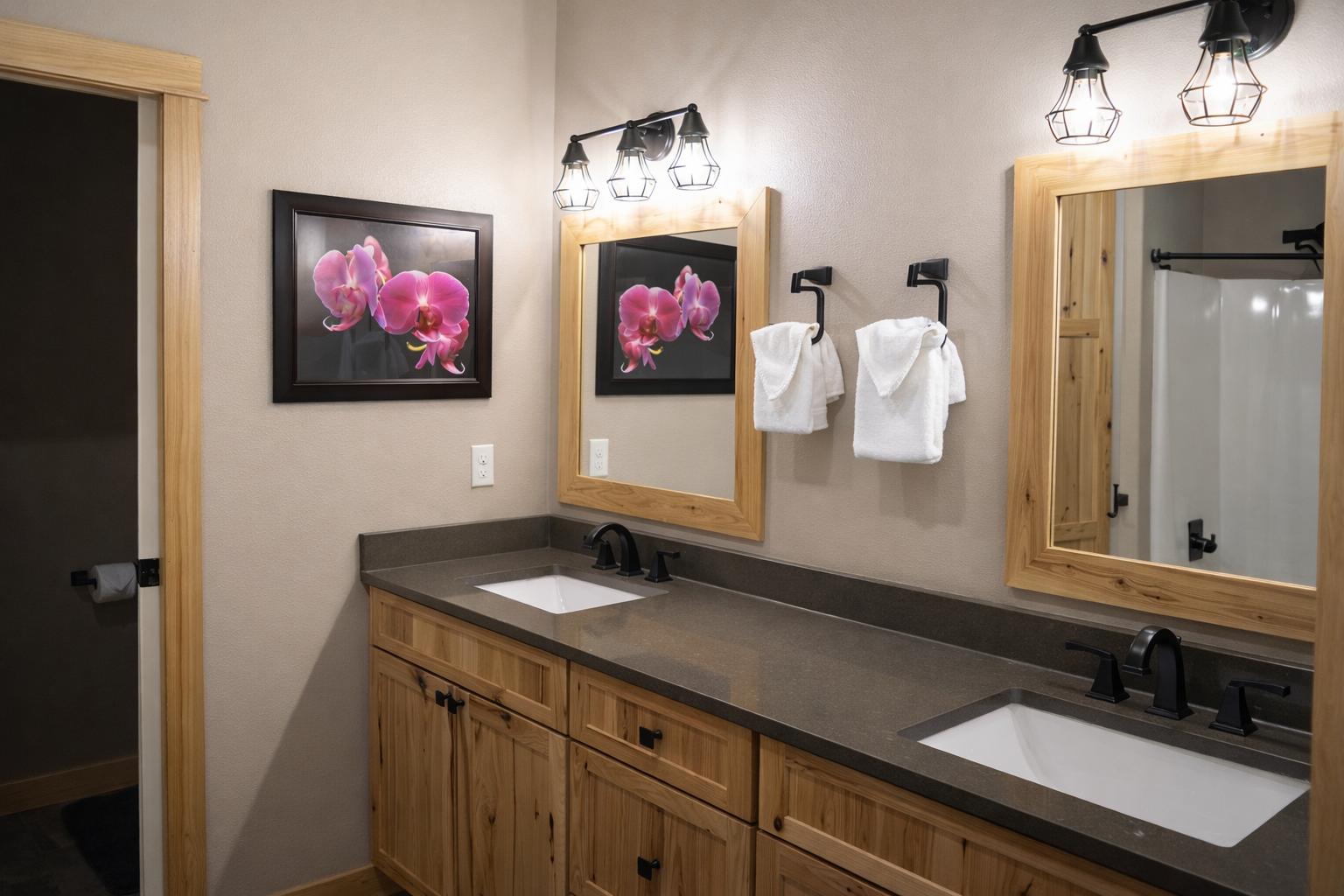 You'll love this stylish double-vanity bathroom with rustic wood cabinets, modern fixtures, and thoughtful touches like plush towels ready for your arrival.
