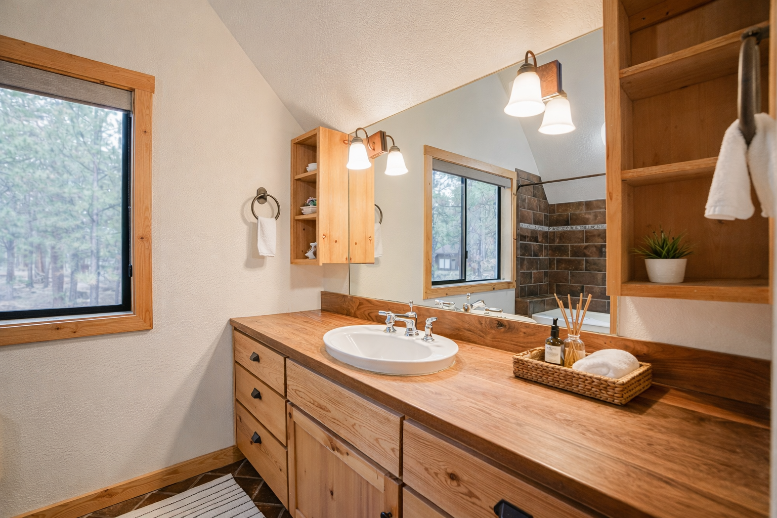 Refresh in your private spa-like bathroom featuring warm wood vanity, modern amenities, and peaceful forest views.