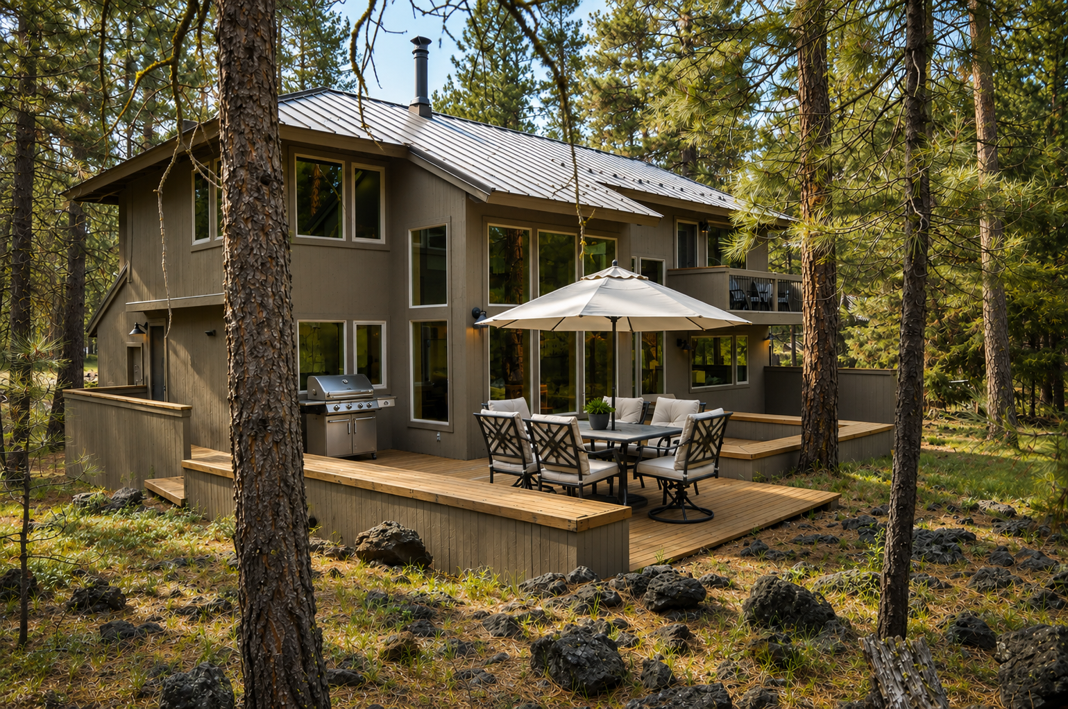 Modern vacation home nestled among towering pines features a spacious deck with dining and grilling areas, perfect for enjoying the serene forest setting and mountain air.