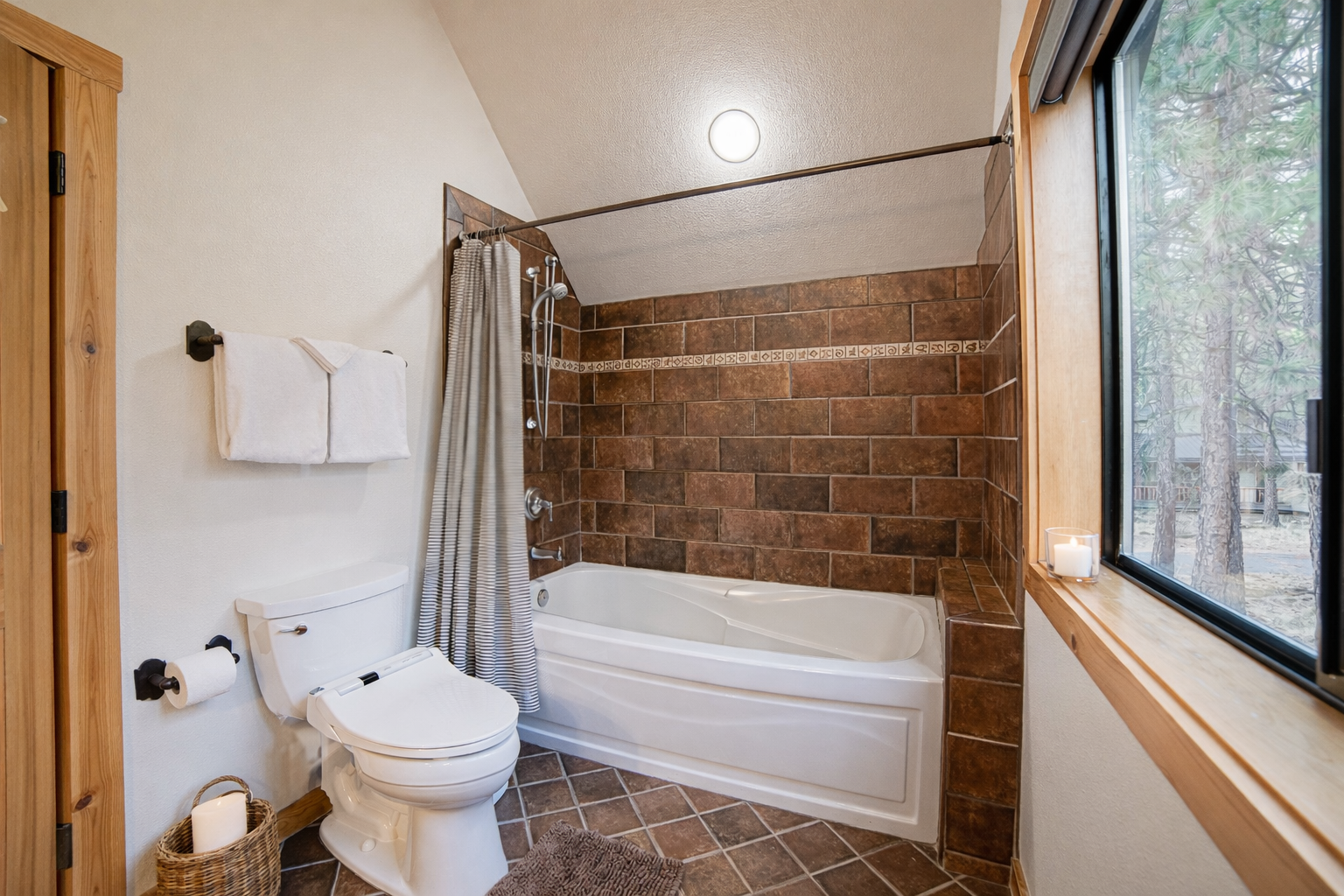 Unwind in your private bathroom featuring a deep soaking tub with beautiful forest views through the window.