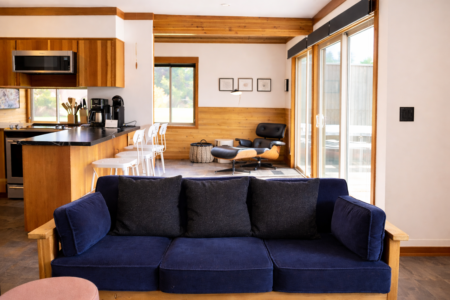 Sink into the plush navy sofa while soaking up natural light from floor-to-ceiling windows in this modern open-concept retreat.