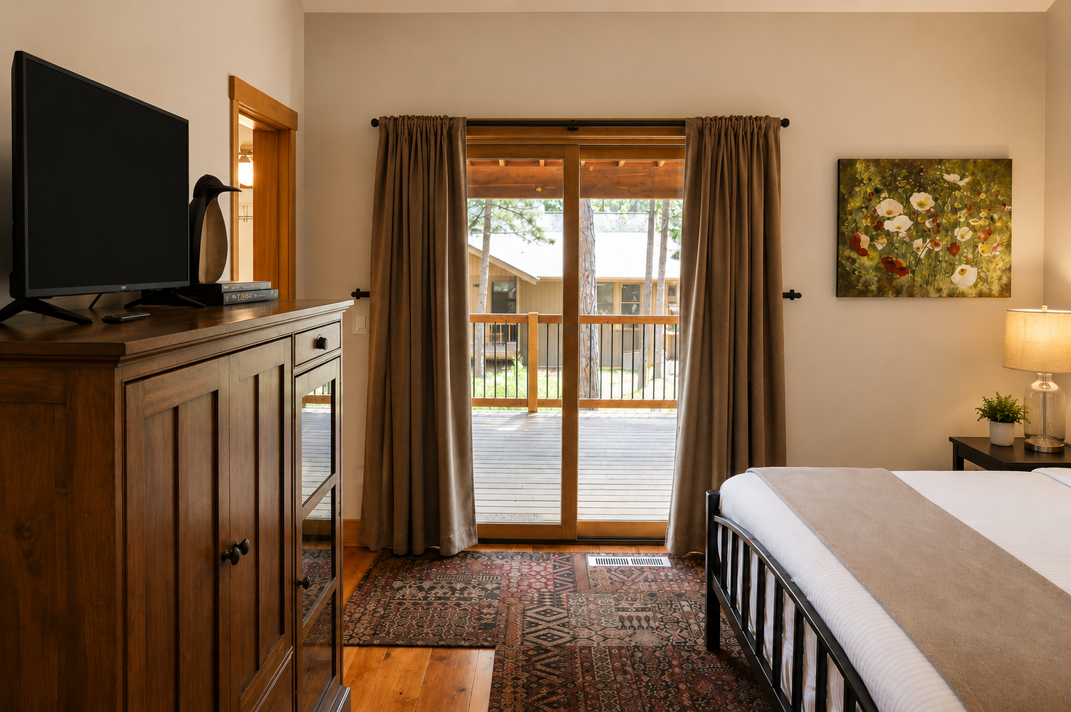 Step into your peaceful retreat with a comfortable queen bed, flat-screen TV, and private balcony access overlooking the grounds. Warm wood tones and thoughtful touches create a welcoming space to unwind.