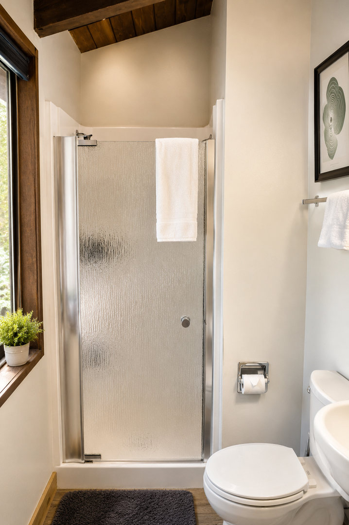 Step into your private bathroom with a bright, modern shower, fluffy fresh towels, and warm wooden accents that make every refresh feel like a spa moment.