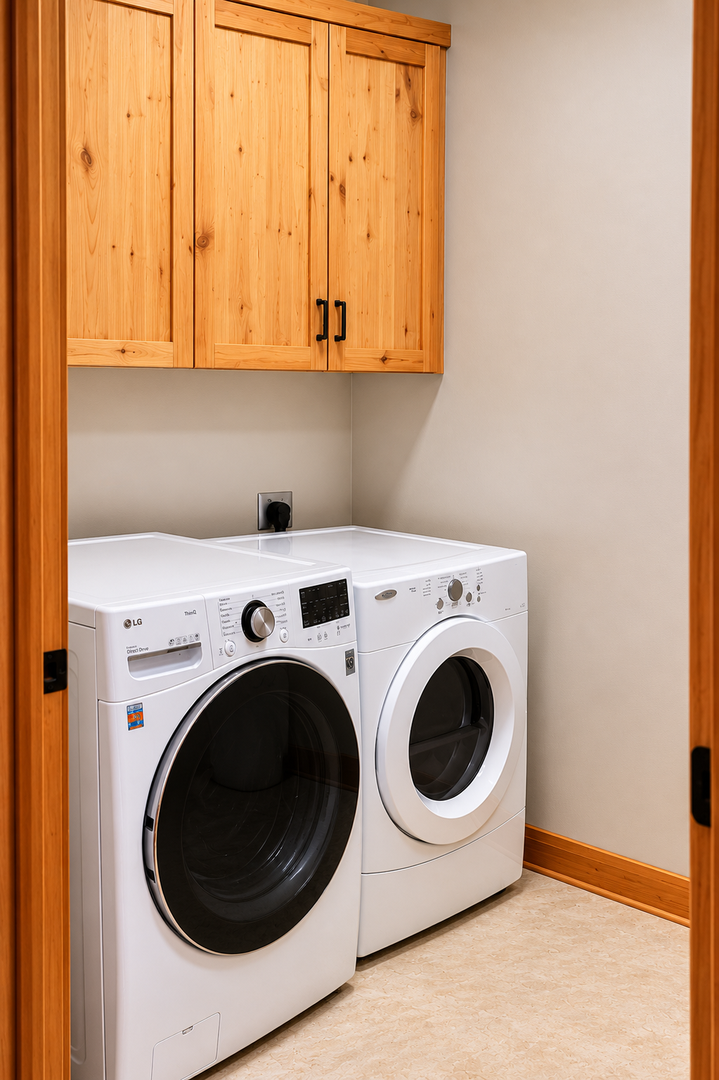 Your dedicated laundry space features a full-size washer and dryer tucked beneath warm wooden cabinets, offering convenient storage and making it easy to refresh your wardrobe during your stay.