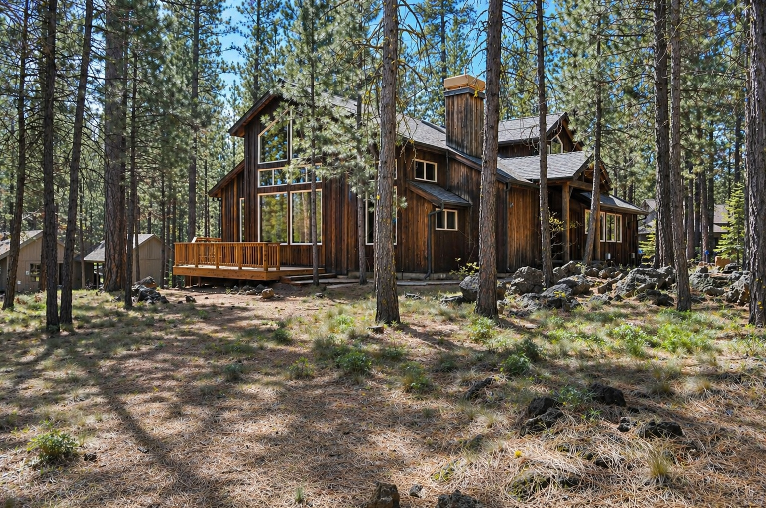 A charming mountain cabin nestled among towering pines, featuring natural wood siding and a welcoming deck surrounded by pristine forest.