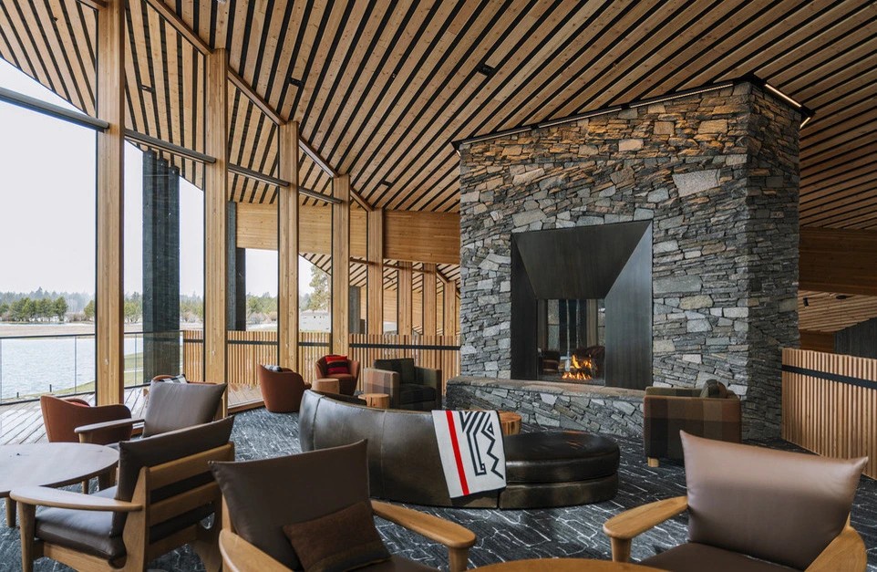 Sink into luxurious leather seating beside the stone fireplace, where warm wood beams create your perfect lakeside retreat.