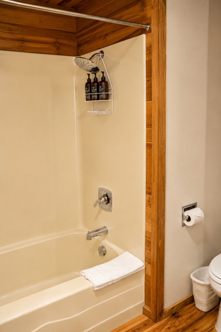 Step into your private retreat with a spacious tub-shower combo featuring a rainfall showerhead and complimentary toiletries—warm wood accents and fresh linens await your relaxation.