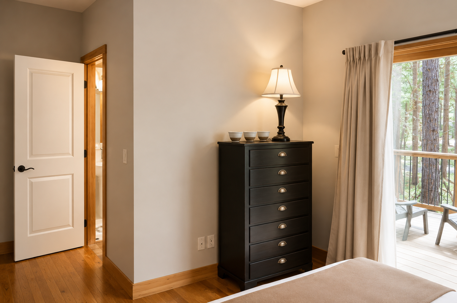 Your peaceful bedroom features warm hardwood floors, ample storage with a classic dresser, and direct access to your private balcony overlooking serene forest views.