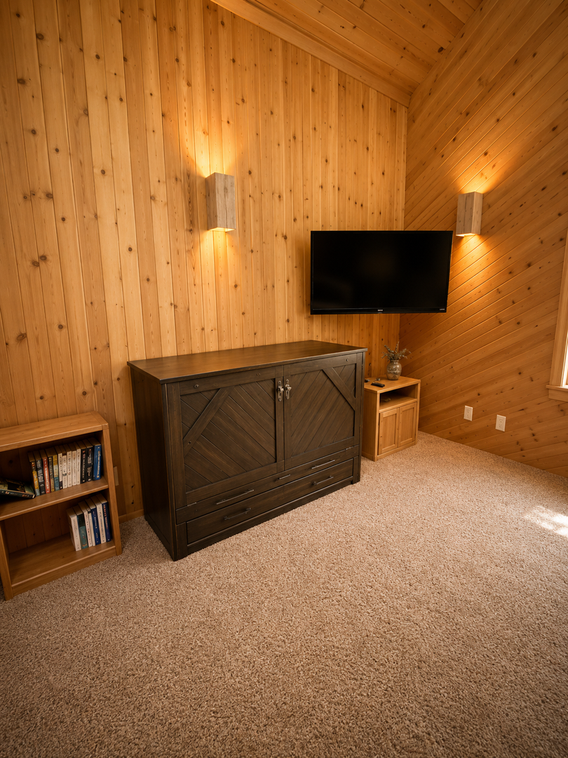 Unwind in your cozy loft bedroom with vaulted pine ceilings, warm ambient lighting, and a flat-screen TV. Plenty of storage keeps your space open and relaxing.