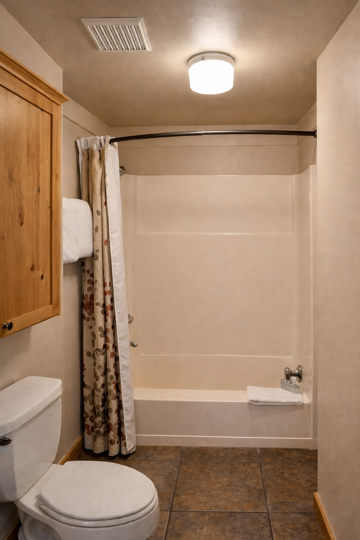 Unwind in your private bathroom featuring a spacious tub-shower combo, warm wood accents, and fresh towels waiting for your arrival.
