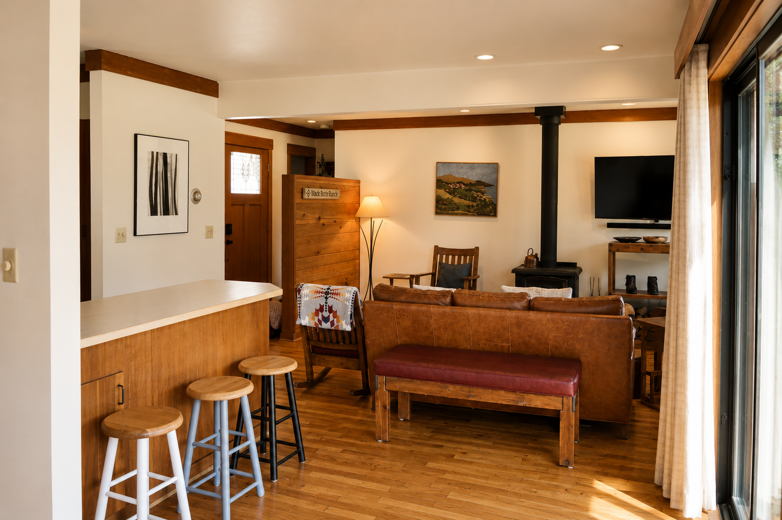 Your open living space invites relaxation with warm wood accents, a cozy fireplace, and a leather sofa perfect for unwinding after exploring. Sunlight filters through sliding doors, while bar seating offers a casual spot to sip morning coffee.