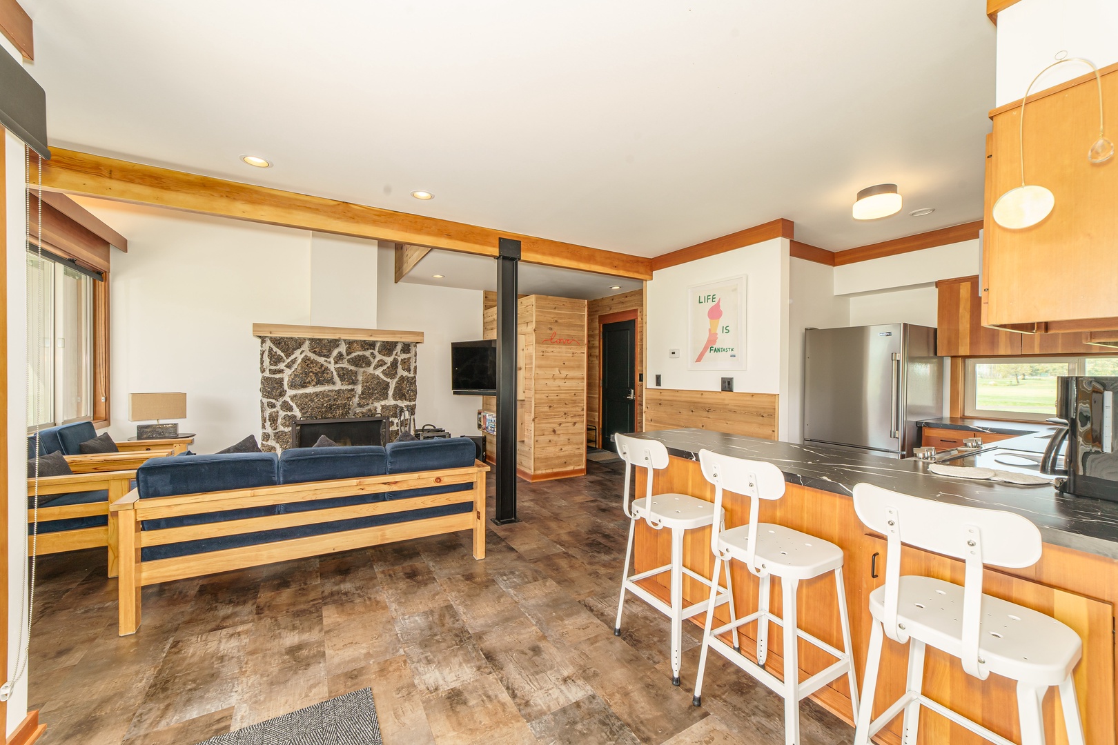Your open-concept retreat features warm wood accents, a cozy stone fireplace, and modern kitchen with island seating for memorable gatherings.