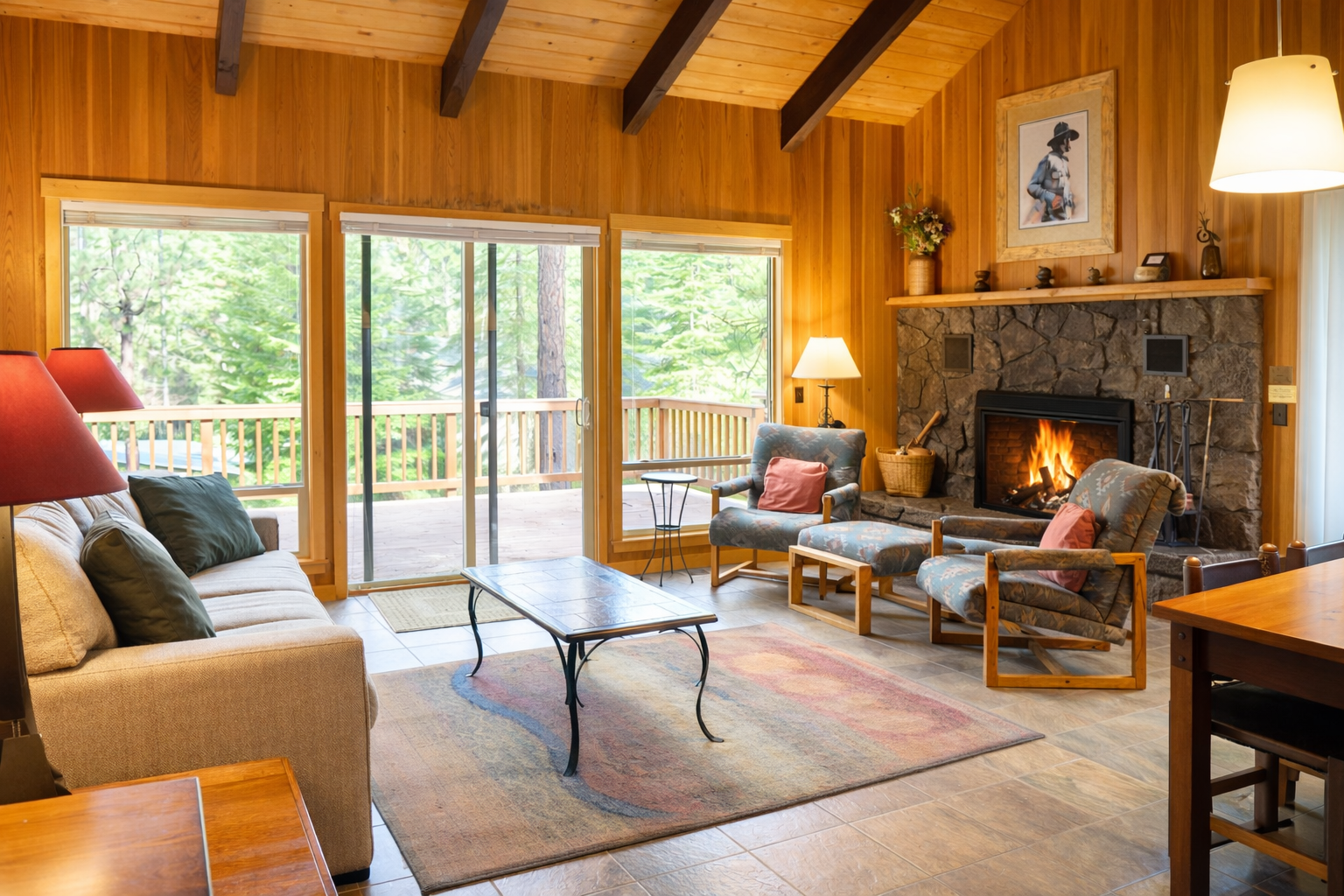 Warm up by the crackling fireplace while enjoying forest views from your cozy living room with exposed beams and balcony access.