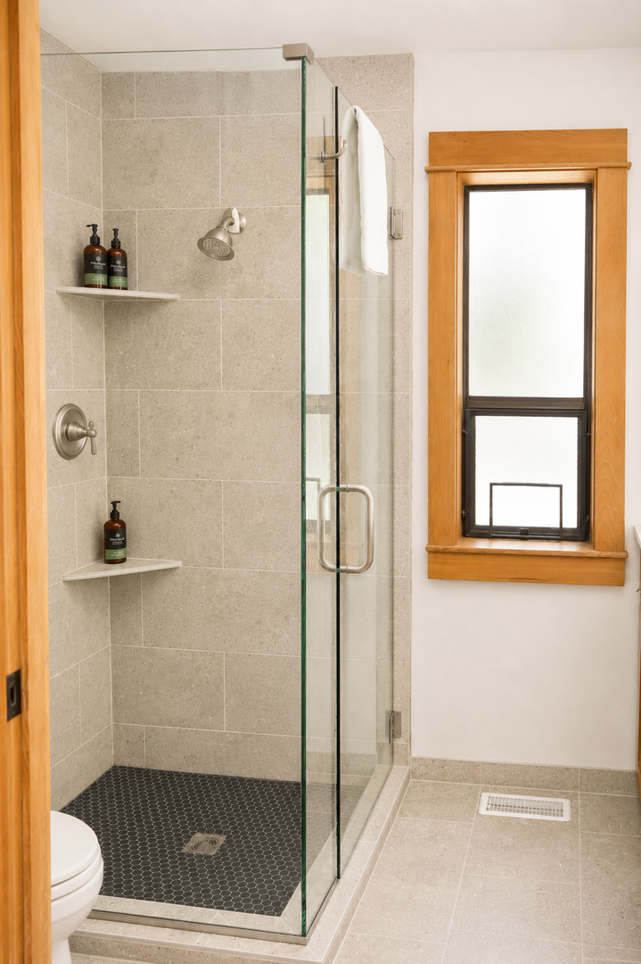 Step into your bright, modern bathroom with a spacious walk-in shower, sleek glass enclosure, and thoughtful shelving stocked with premium toiletries—a refreshing private retreat awaits you.