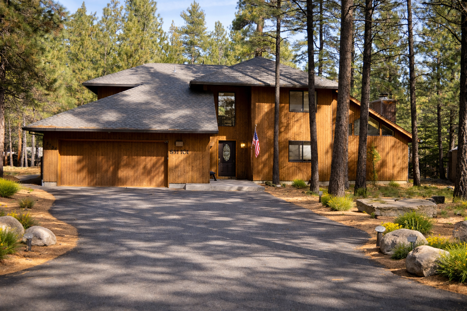 Stunning cedar-clad mountain retreat nestled among towering pines with spacious driveway and natural stone landscaping.
