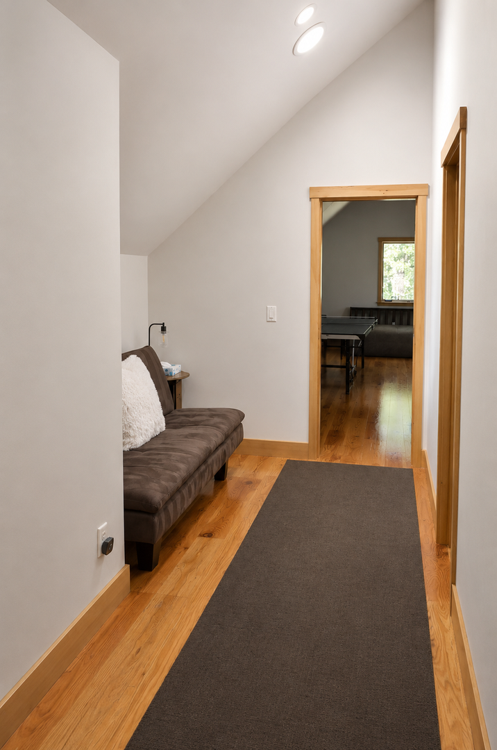 You'll find a peaceful retreat in this bright upstairs hallway, complete with a cozy lounge nook and warm hardwood underfoot—perfect for reading or unwinding between rooms.