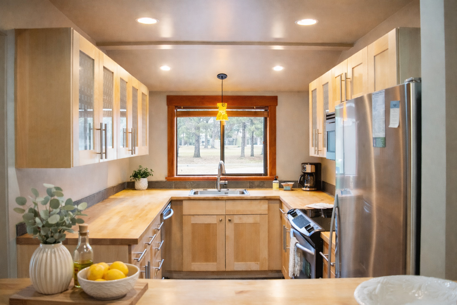 Your fully equipped kitchen welcomes you with warm wood cabinets, granite counters, and forest views through the window.