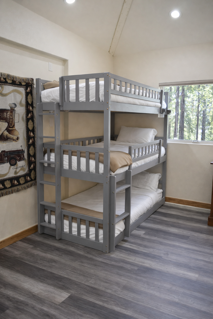 Your cozy triple bunk setup maximizes space while keeping everyone comfortable, with soft linens and natural light streaming through the window.