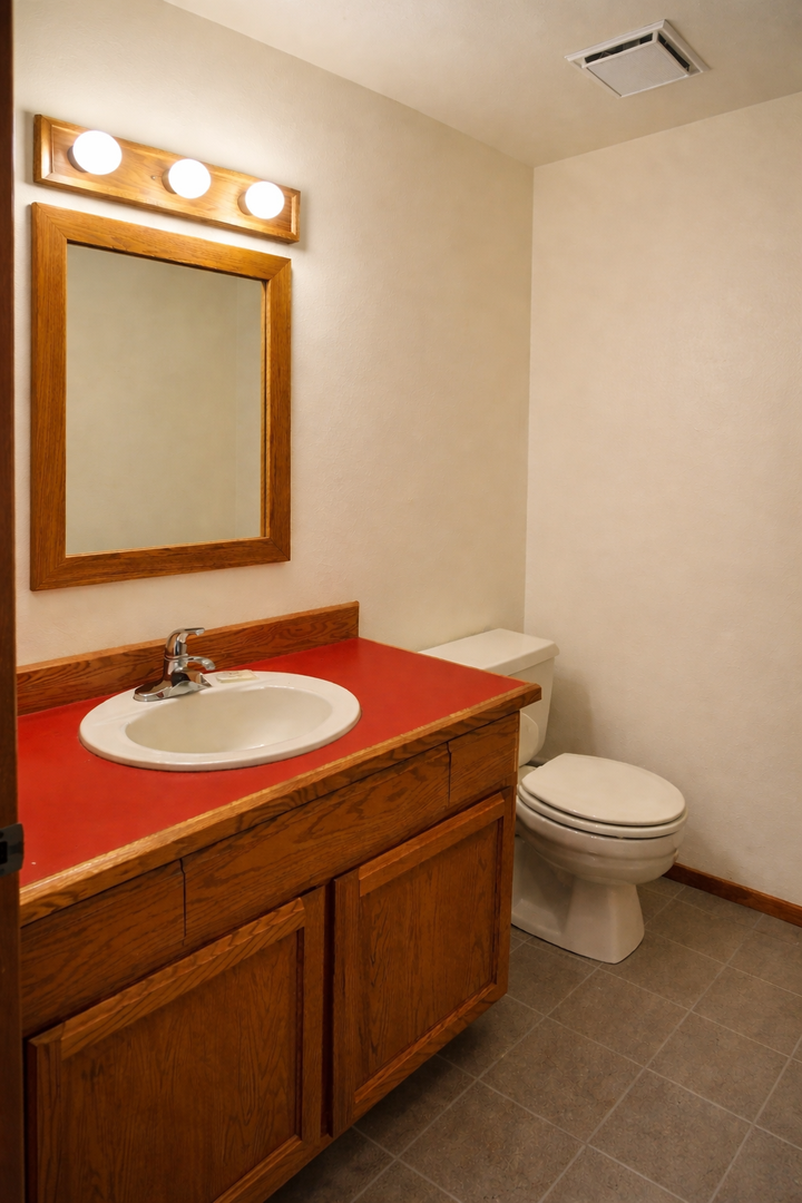 Your private bathroom features warm wood vanity with bright Hollywood-style lighting and spacious comfort.