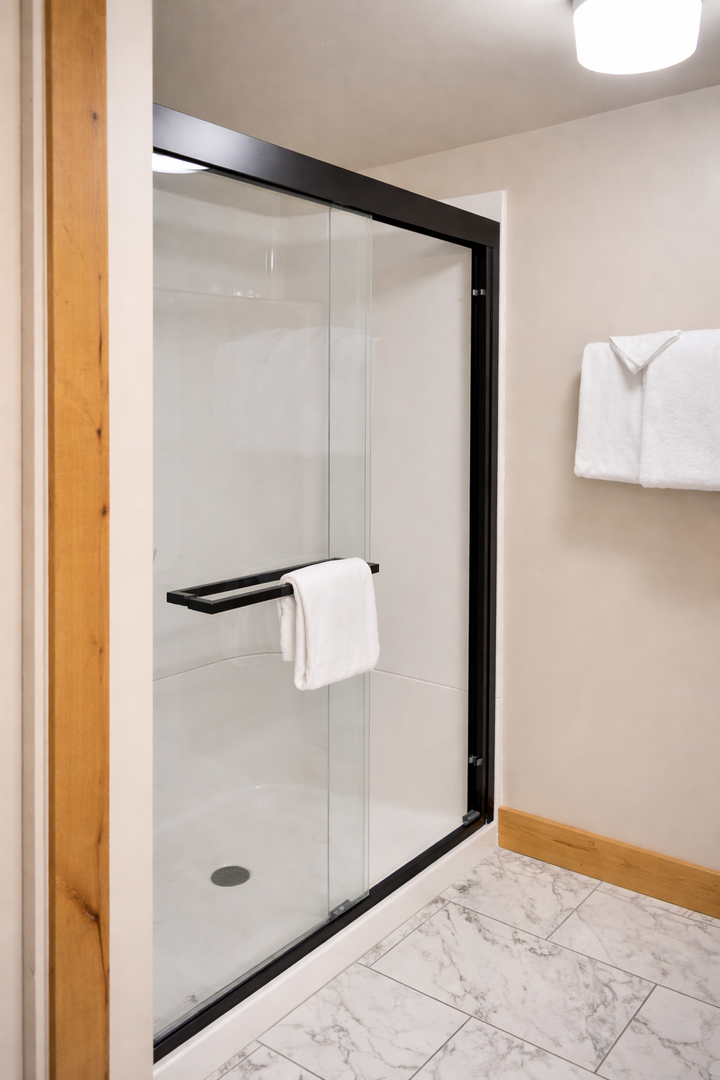 Step into your sleek glass shower with modern fixtures and fresh towels waiting for you.