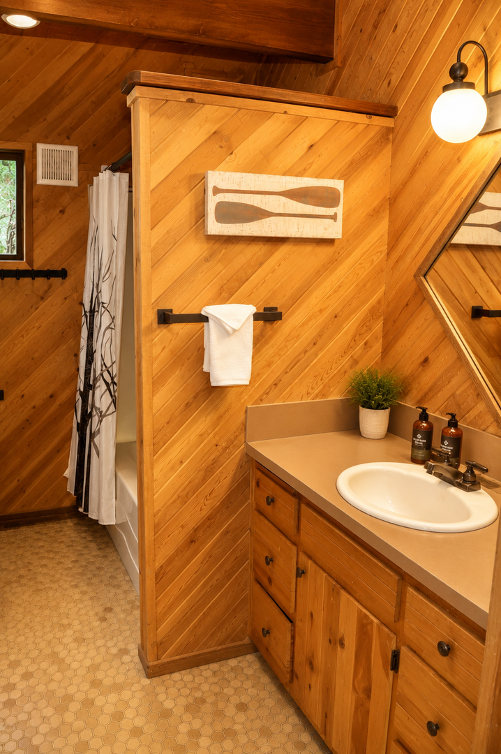 Unwind in this charming cabin-style bathroom with warm wood paneling and thoughtful details. Fresh towels, quality toiletries, and a cozy ambiance welcome you after your adventures.