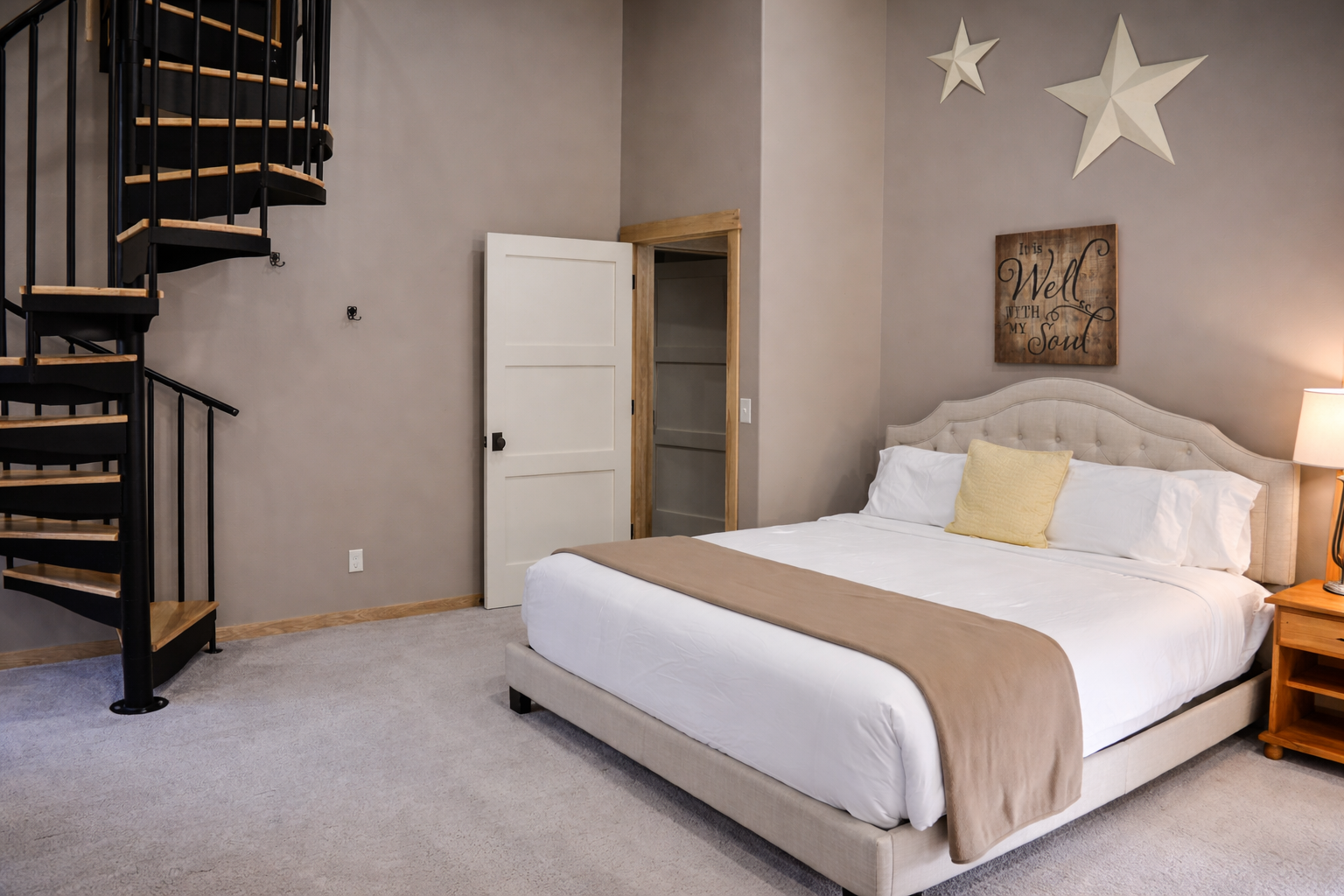 Unwind in your stylish bedroom with plush bedding, charming decor, and a striking spiral staircase leading to your private loft space above.