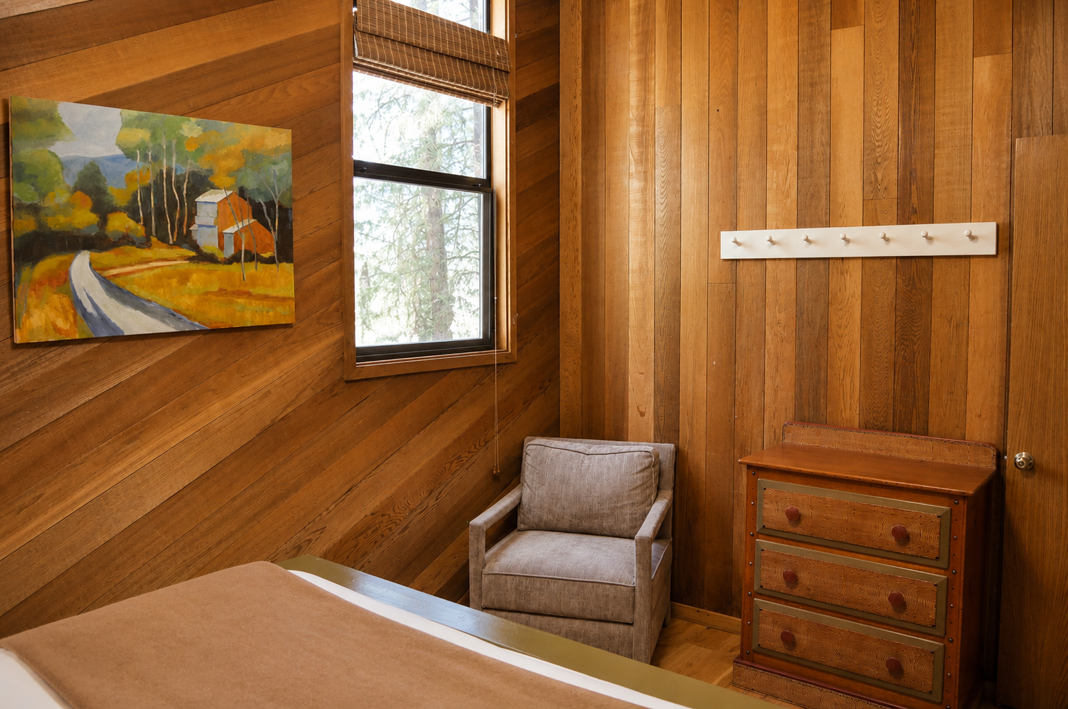 Settle into your cozy reading nook by the window, where warm wood tones and autumn-inspired art create a peaceful retreat. Store your belongings in the charming dresser and unwind in comfort.