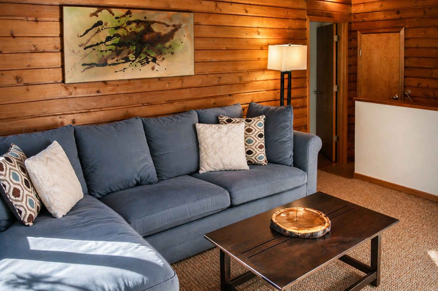 Sink into your cozy sectional surrounded by warm wood walls, where soft pillows and gentle lighting create the perfect retreat.