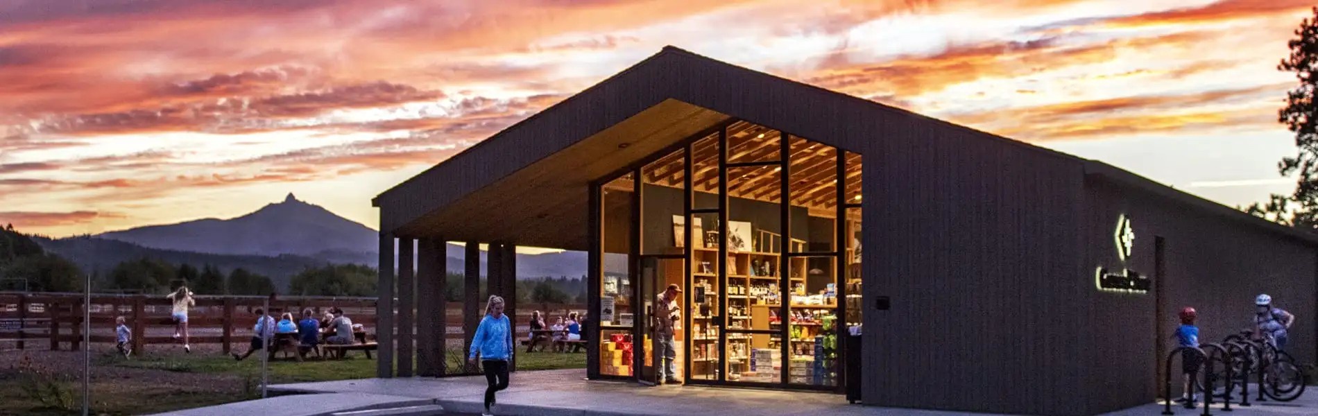 Modern visitor center welcomes guests with stunning mountain backdrop during golden hour sunset.