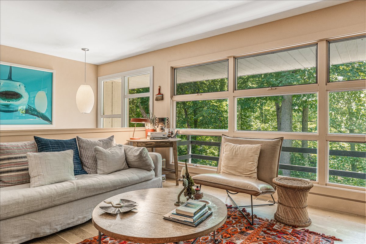 Unwind in your bright living space with floor-to-ceiling windows showcasing leafy tree views and modern comfort.