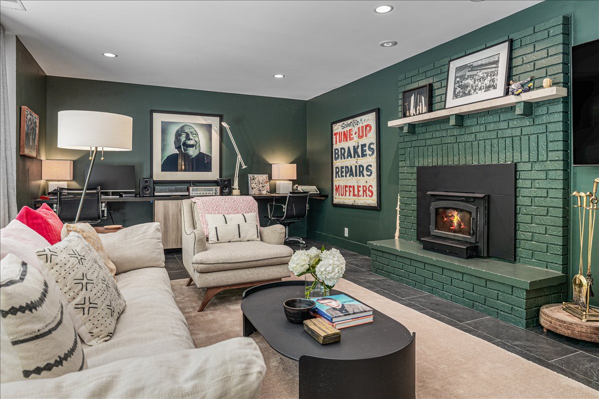 Cozy up in your stylish living room featuring a stunning green brick fireplace, comfortable seating, and curated artwork that creates the perfect atmosphere for relaxing evenings.
