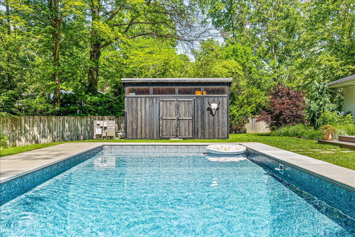 Dive into your private oasis with crystal-clear pool waters and charming rustic shed backdrop.