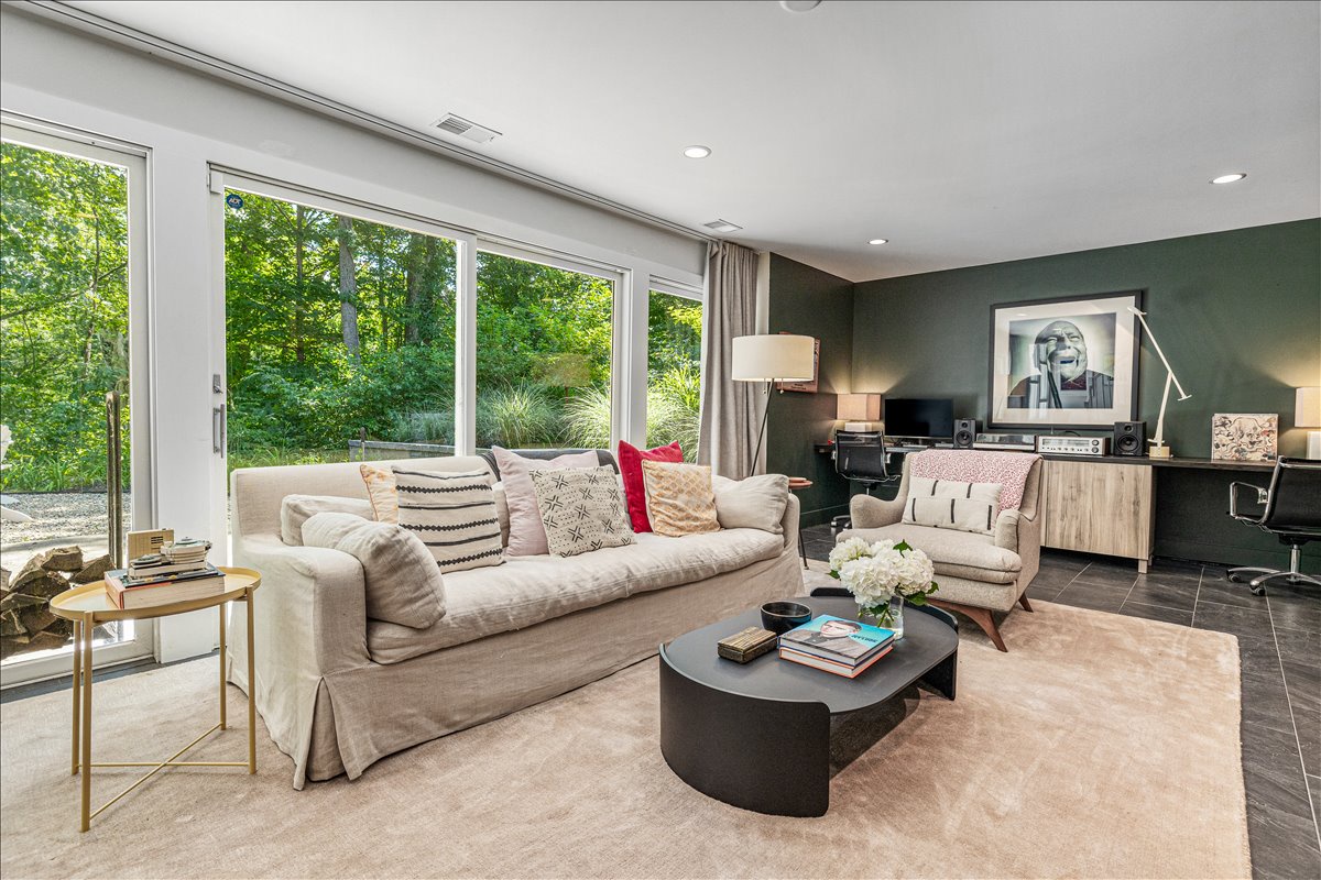 Unwind in your stylish living room where natural light floods through floor-to-ceiling windows, revealing lush garden views.