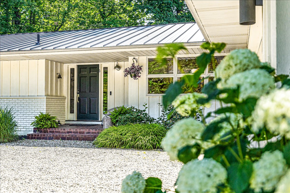 Charming front entrance with lush landscaping and beautiful hydrangeas creates a welcoming arrival experience at this peaceful retreat.