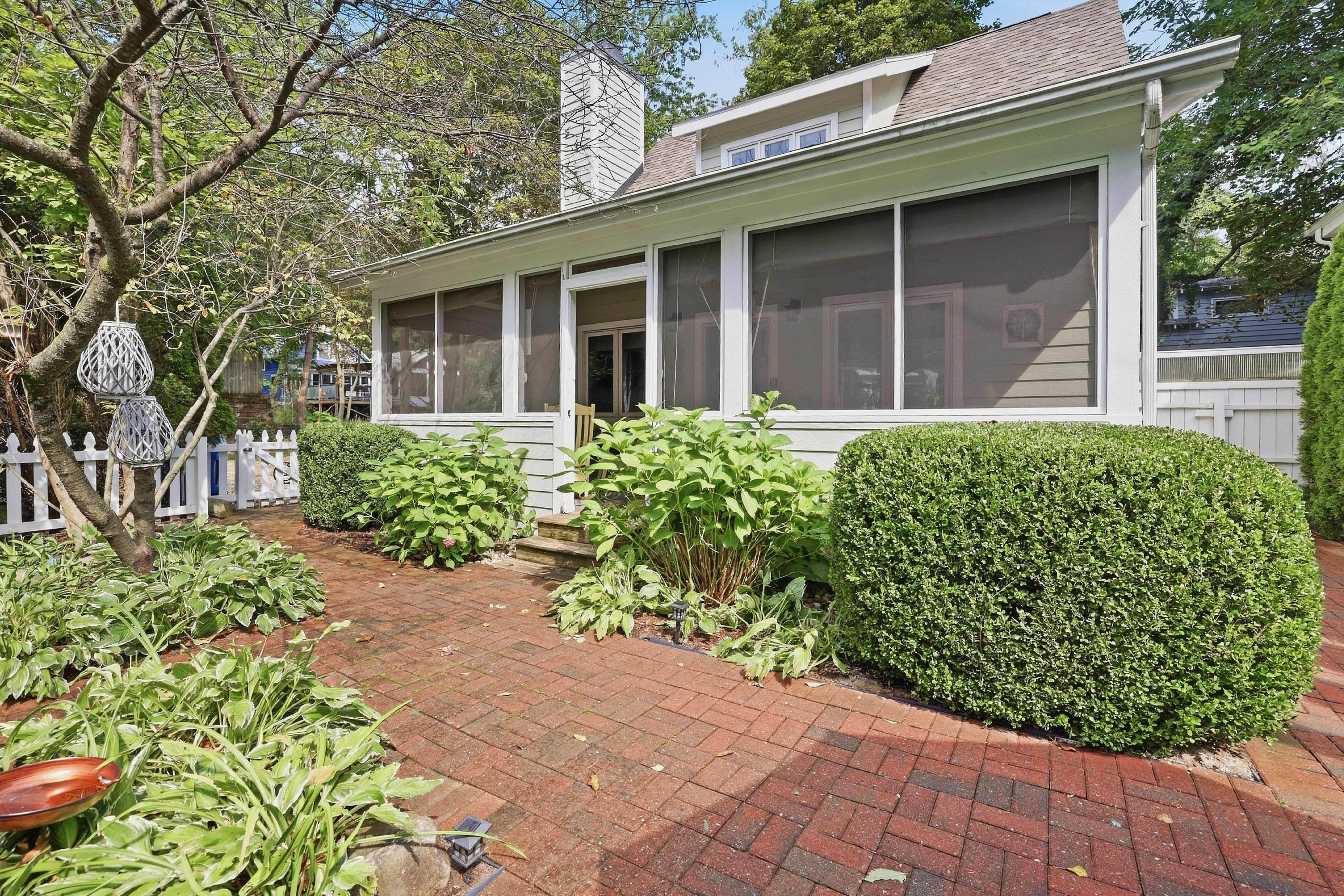 A charming screened-in porch surrounded by lush greenery and mature trees offers a peaceful outdoor retreat at this property.